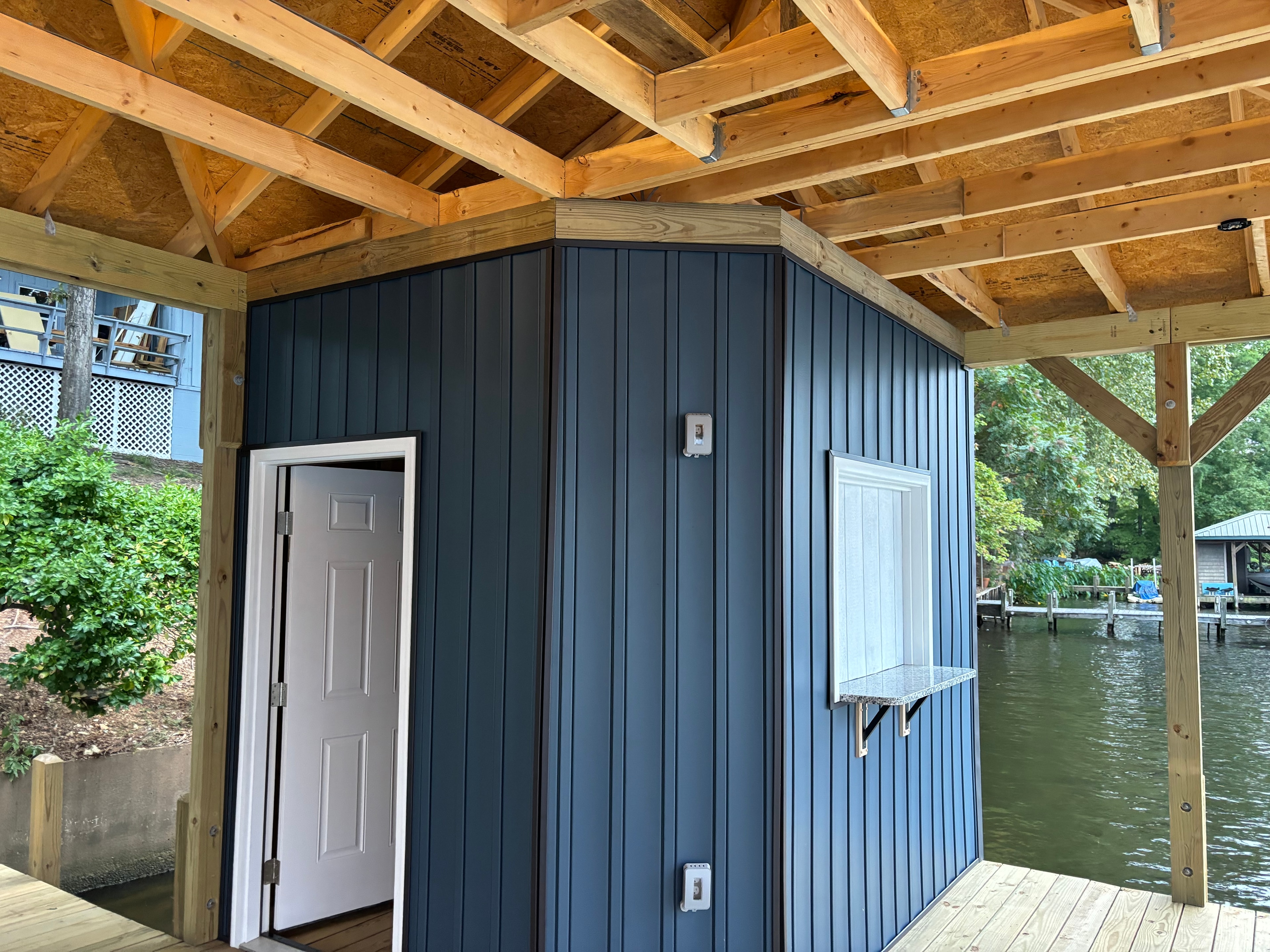 SHT Construction — boathouse storage room with blue corrugated siding and exposed rafters