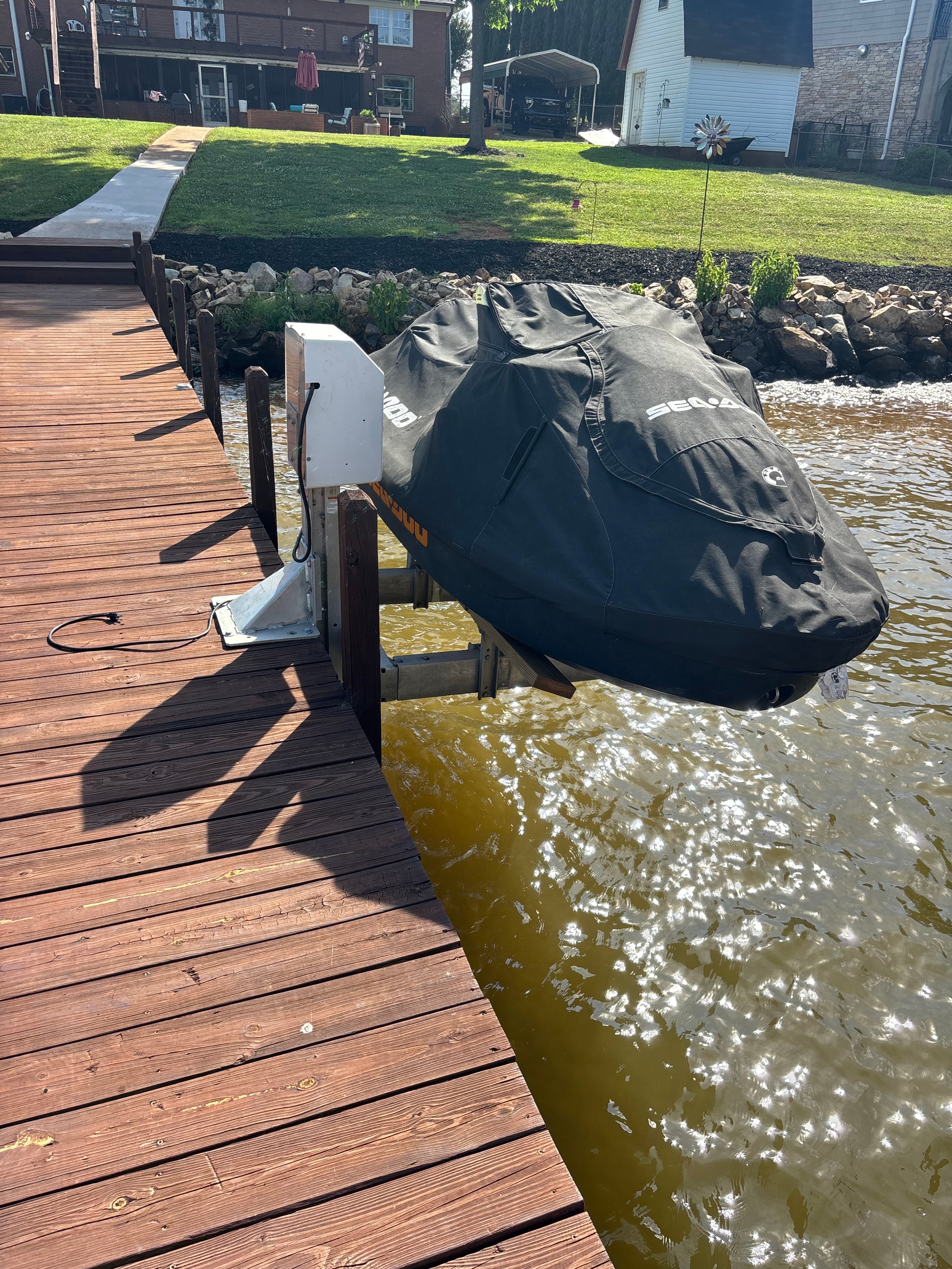 SHT Construction — Doozie boat lift with Sea-Doo on dock, riprap shoreline and green lawn in background